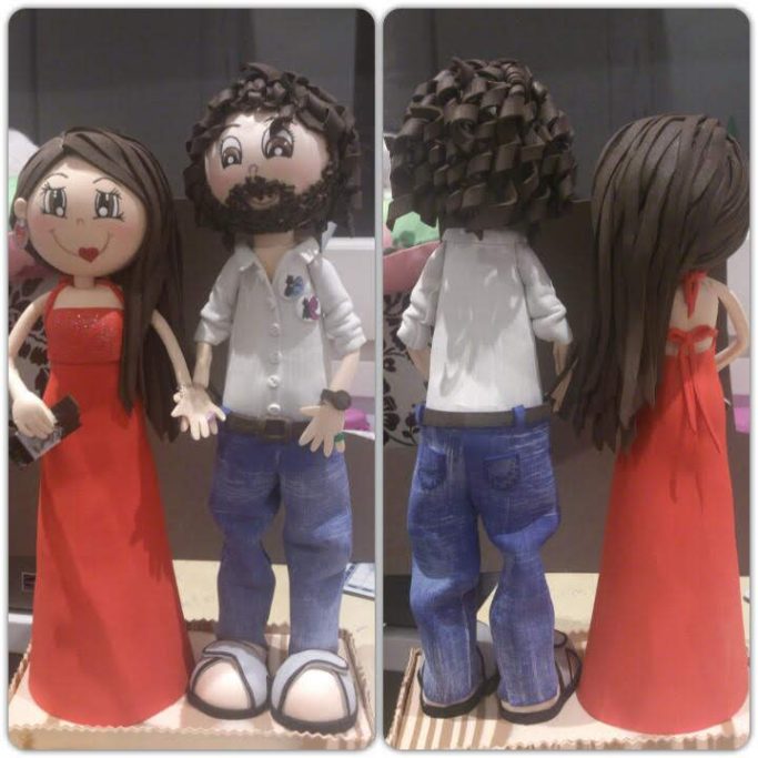 Pareja de figuras de boda, una mujer con vestido rojo y un hombre con cabello rizado.