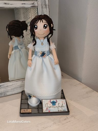 fofucha personalizada,  con vestido de comunión blanco y cinturón azul claro con flores, con el pelo recogido.