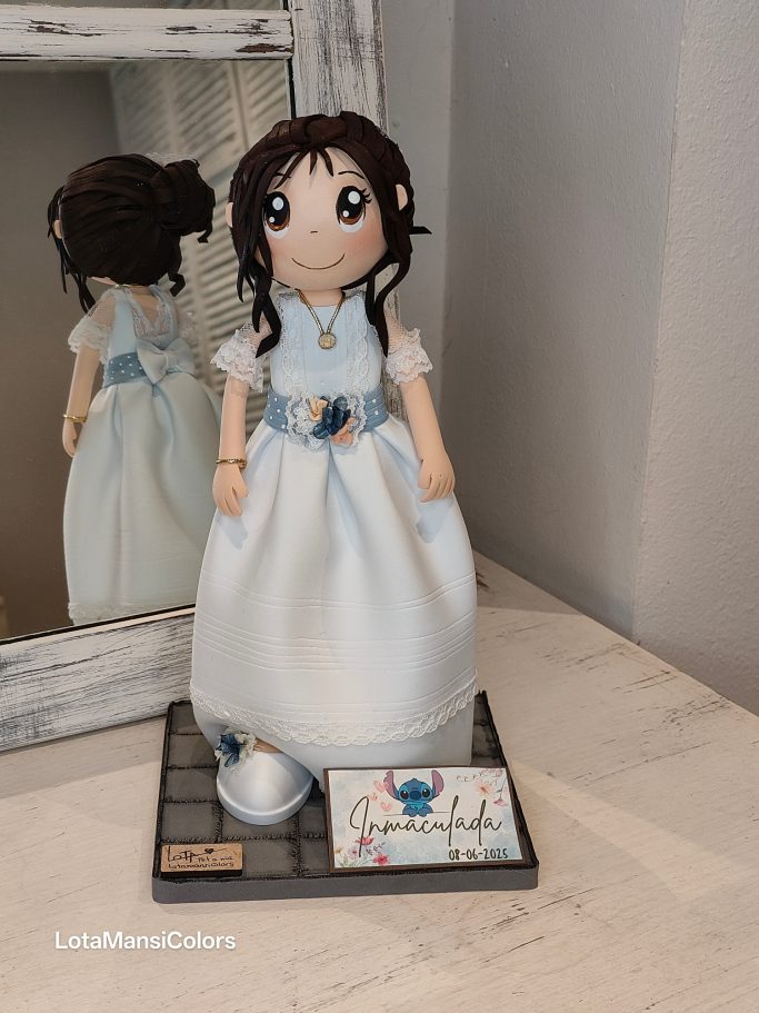 Muñeca con vestido blanco y cinturón azul claro, con el pelo recogido.