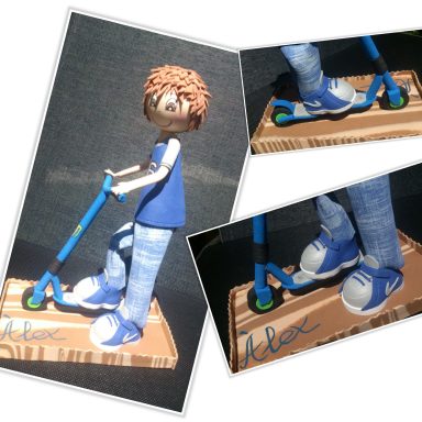 Figurita de niño en patinete, con camiseta azul y pantalones de tejano, base de madera.