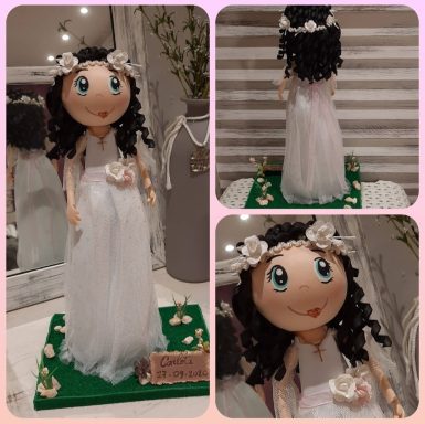 Muñeca con vestido blanco y cabello rizado, adornada con flores en la cabeza.