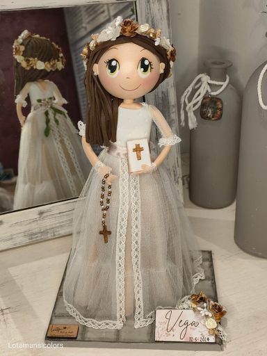 Fofucha personalizada de comunión vestida de blanco, con corona de flores, sosteniendo un libro y un rosario.