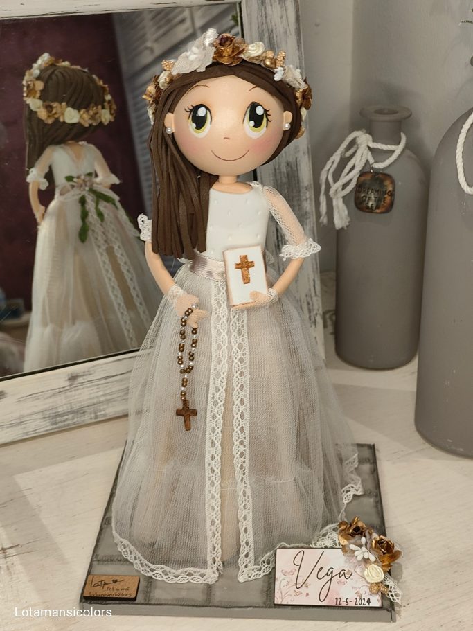 Fofucha de comunión vestida de blanco con corona de flores, sosteniendo un libro y un rosario.
