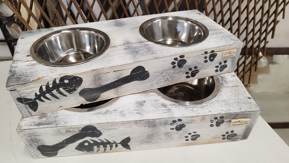 Soporte de comida para mascotas de madera con cuencos de acero inoxidable y decoración de huesos y patas.