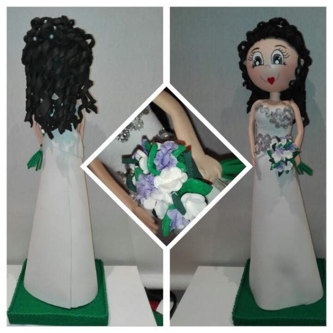 Muñeca con cabello rizado, vestido blanco y ramo de flores en la mano.