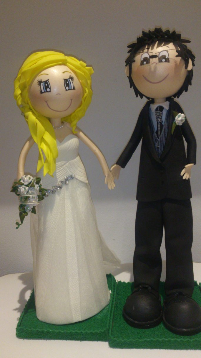 Figuras de novios, ella con vestido blanco y ramo, él con traje oscuro.