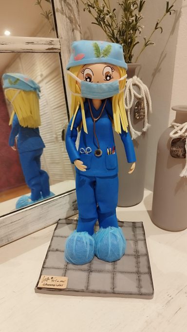Fofucha personalizada, vestida de azul con gorro y mascarilla, con detalles médicos.