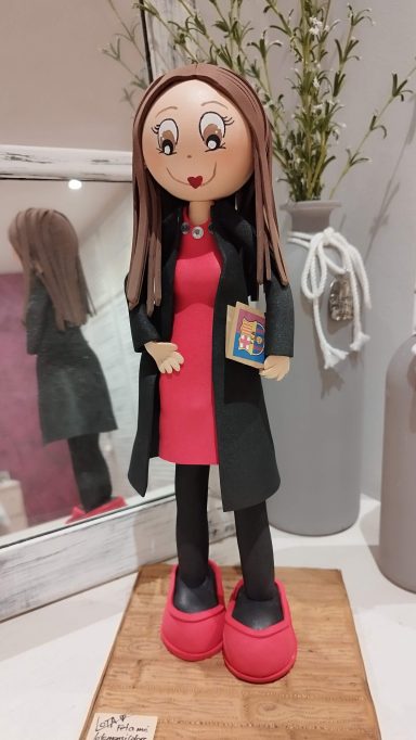 fofucha personalizada con cabello largo, vestido rojo, abrigo negro y zapatos rojos de tacón, con libreta del Barça