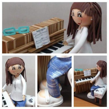 Muñeca de cerámica tocando un piano, con gafas sobre el instrumento y pantalones de mezclilla.
