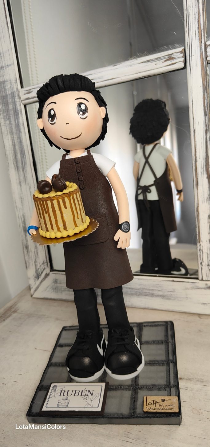 Muñeco con un pastel, vestido con un delantal, y jersey blanco