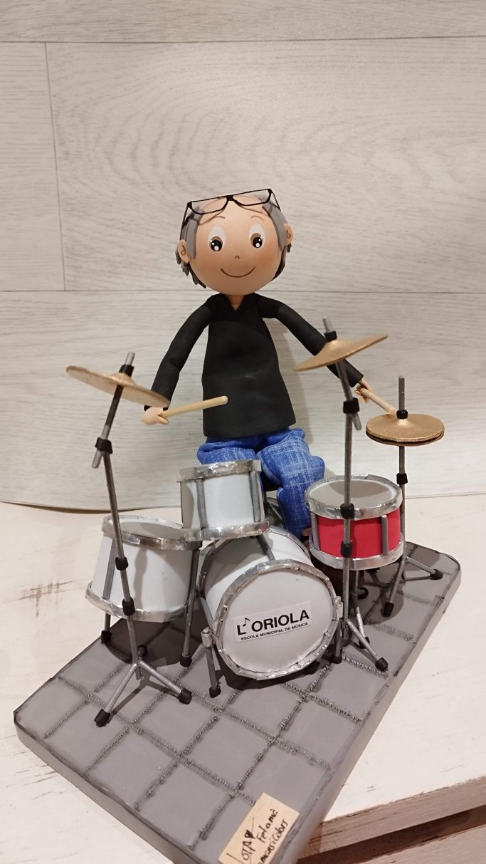 Muñeco de un músico tocando la batería, con las gafas en la cabeza y cabello canoso