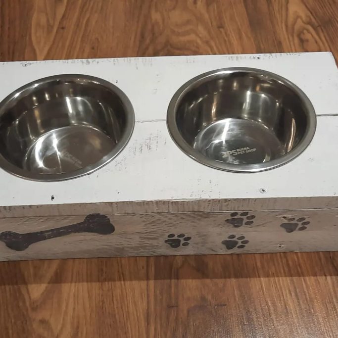 Comedero doble para mascotas con base de madera y tazones de acero inoxidable.