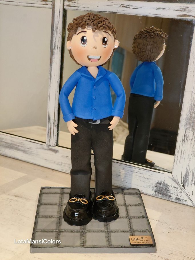 Muñeco personalizado de un chico con camisa azul, pantalones negros y zapatos de charol, sonriendo.