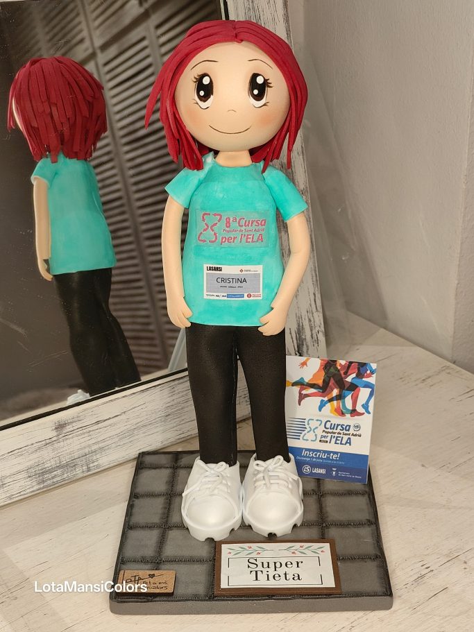 Muñeca de pelo caoba con camiseta azul turquesa, pantalones negros y zapatillas blancas, participando en una carrera a beneficio del ELA