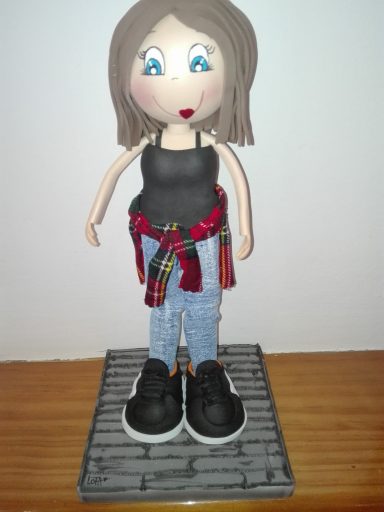 Muñeca  con cabello corto, camiseta negra y camisa de cuadros atada a la cintura, pantalones de mezclilla y zapatillas