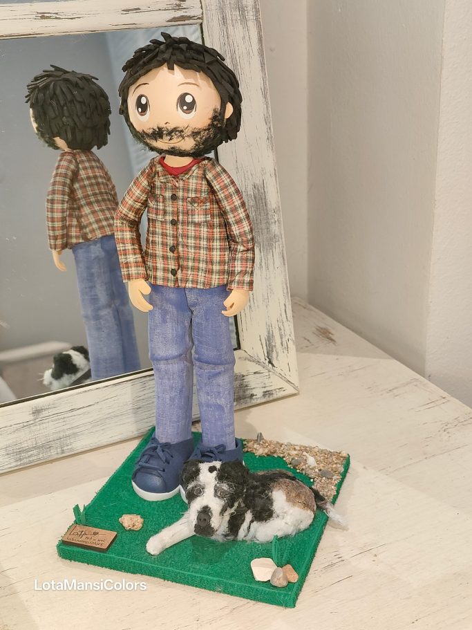 Muñeco hombre con camisa de cuadros y tejanos azules con su  perro al que le falta una patita, sobre una base verde de césped.