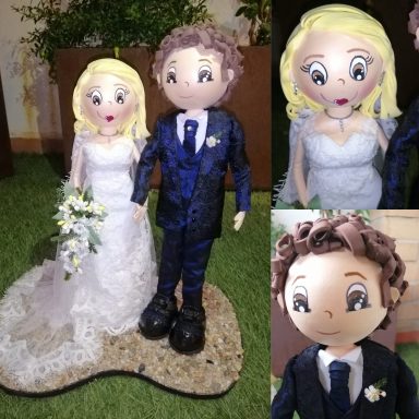 fofuchas personalizadas, pareja de novios ella vestido encaje con cola blanco, el con traje azul marino, en una base de arena de playa